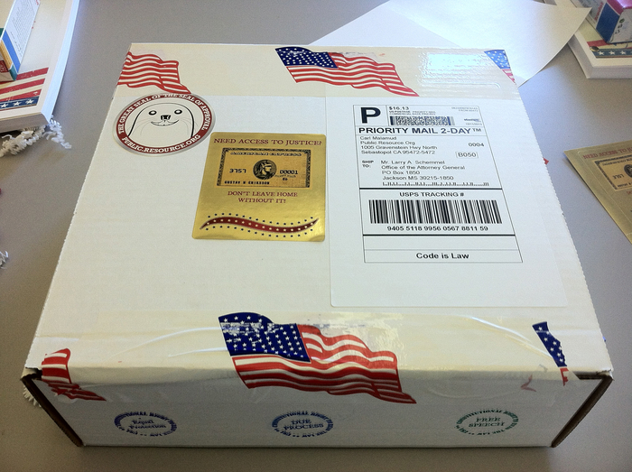 Step 7. The box is sealed with American Flag packing tape and stickered with a facsimile of a major credit card and the saying "Need Access to Justice? Don't Leave Home Without It." The Great Seal of the Seal of Approval is used to authenticate the source