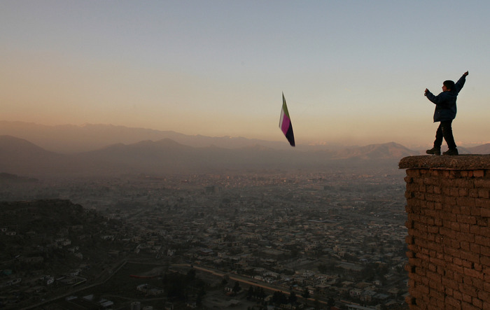 A boy flies a kite along a hill overlooking the city of Kabul at sunset. Kite flying was banned under the Taliban rules for years.