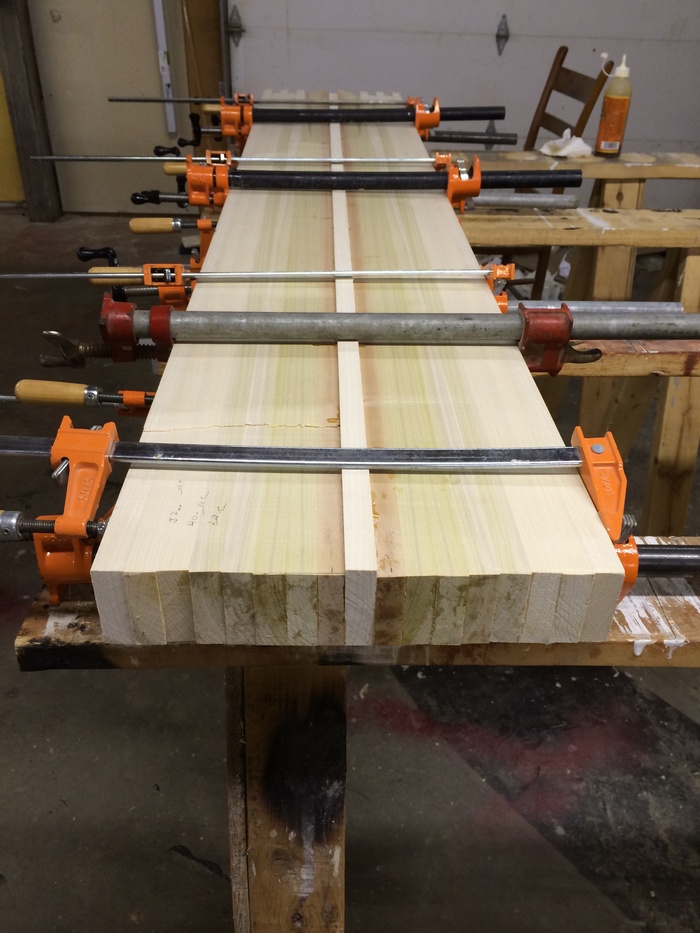 A core block made up of vertically laminated Poplar and Birch dries in a set of clamps.